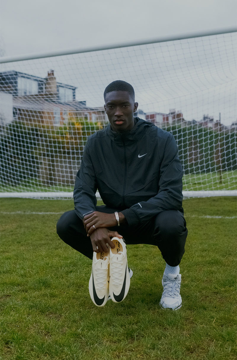 Pape Daouda Diong et ses chaussures Nike sur le terrain d'entraînement de Chelsea Pape Daouda Diong accroupi sur un terrain d'entraînement de Chelsea, tenant une paire de Nike.