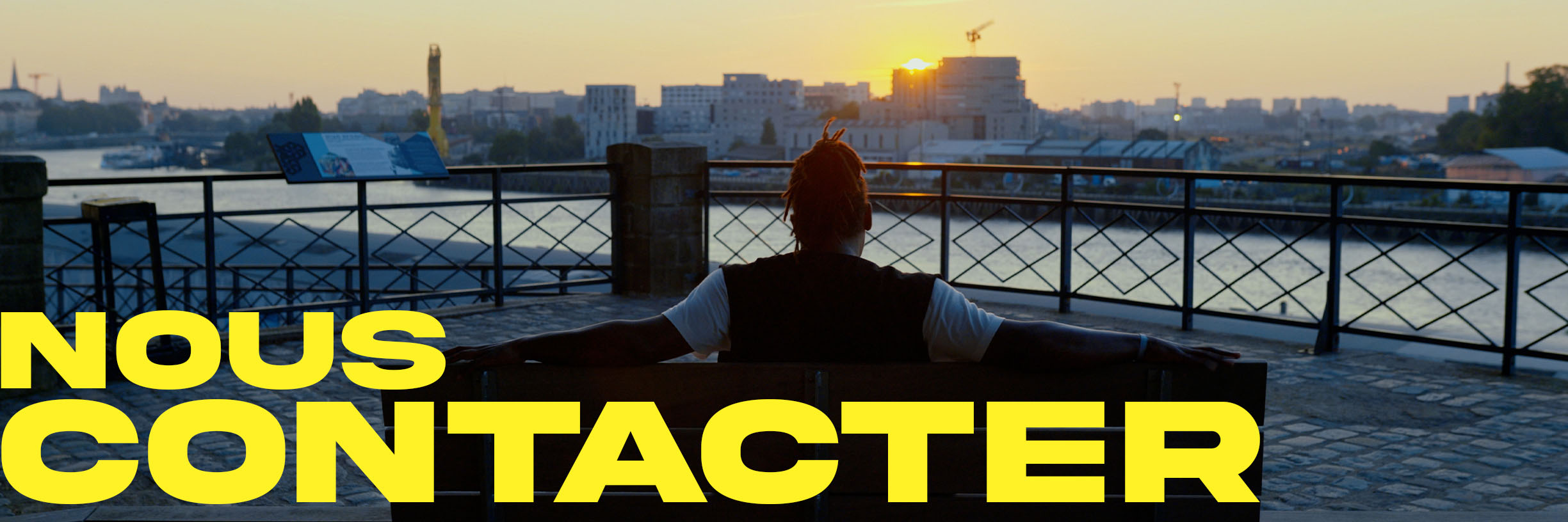 Homme de dos face à un coucher de soleil sur la ville de Nantes. Contactez Great Plains Productions pour vos productions audiovisuels.