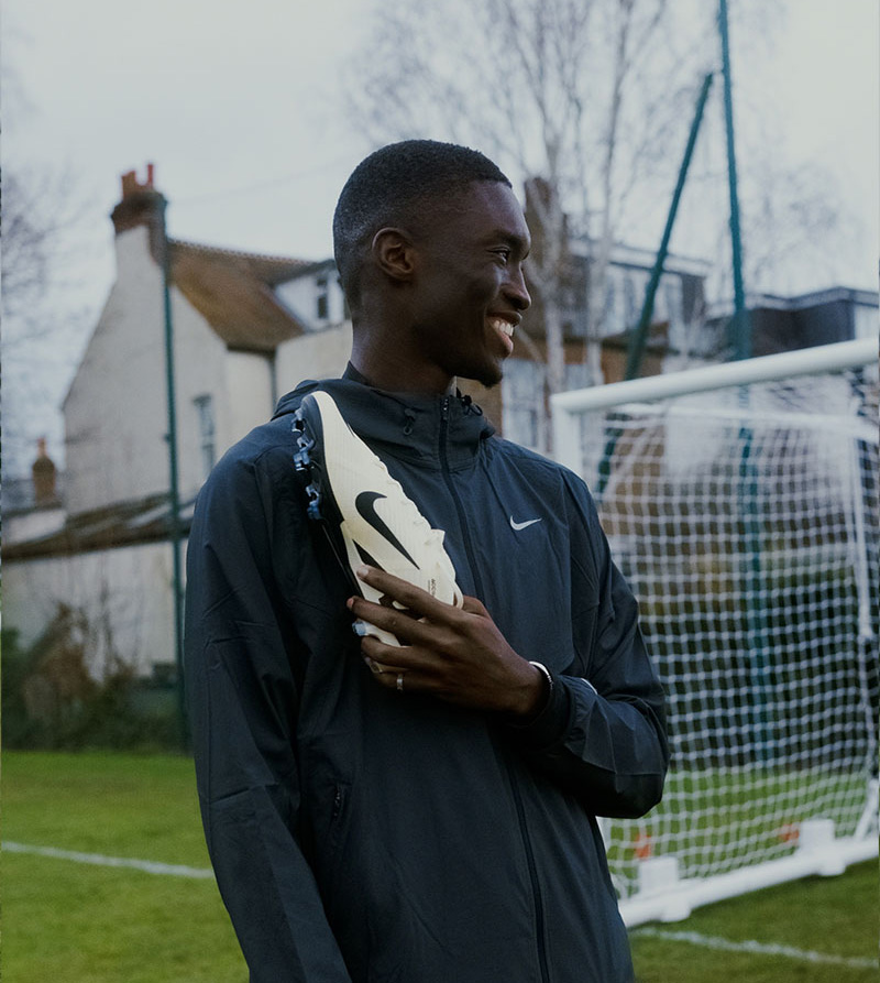 Pape Diong souriant et portant une chaussure Nike sur un terrain de foot
